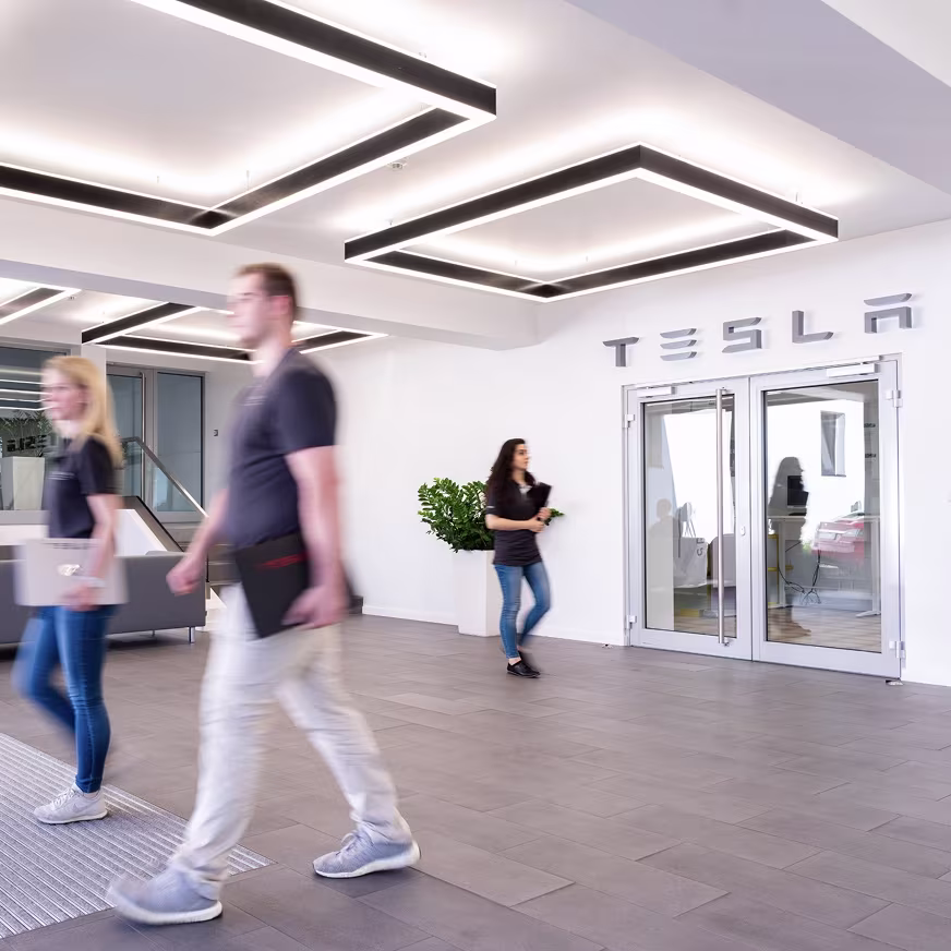 Employees walking around in a Tesla building lobby