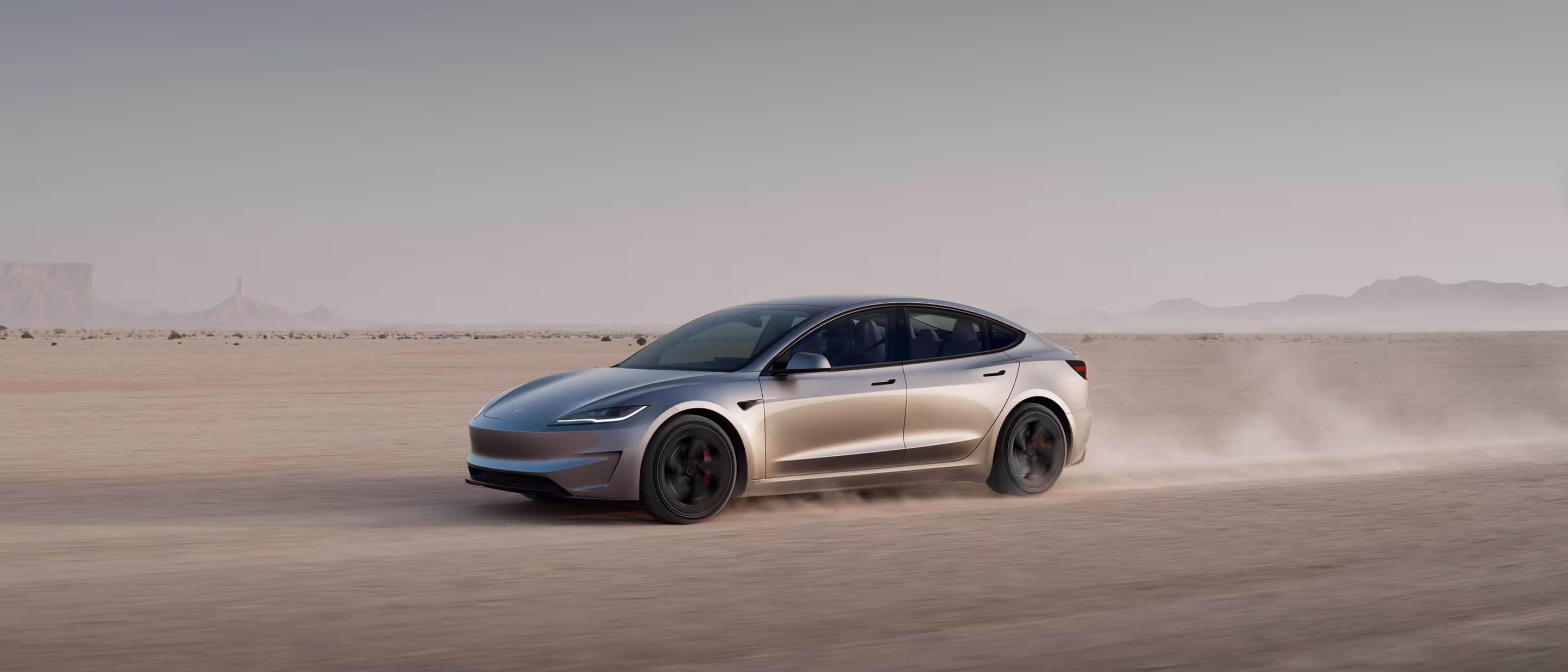 Red Model 3 driving on mountainous road