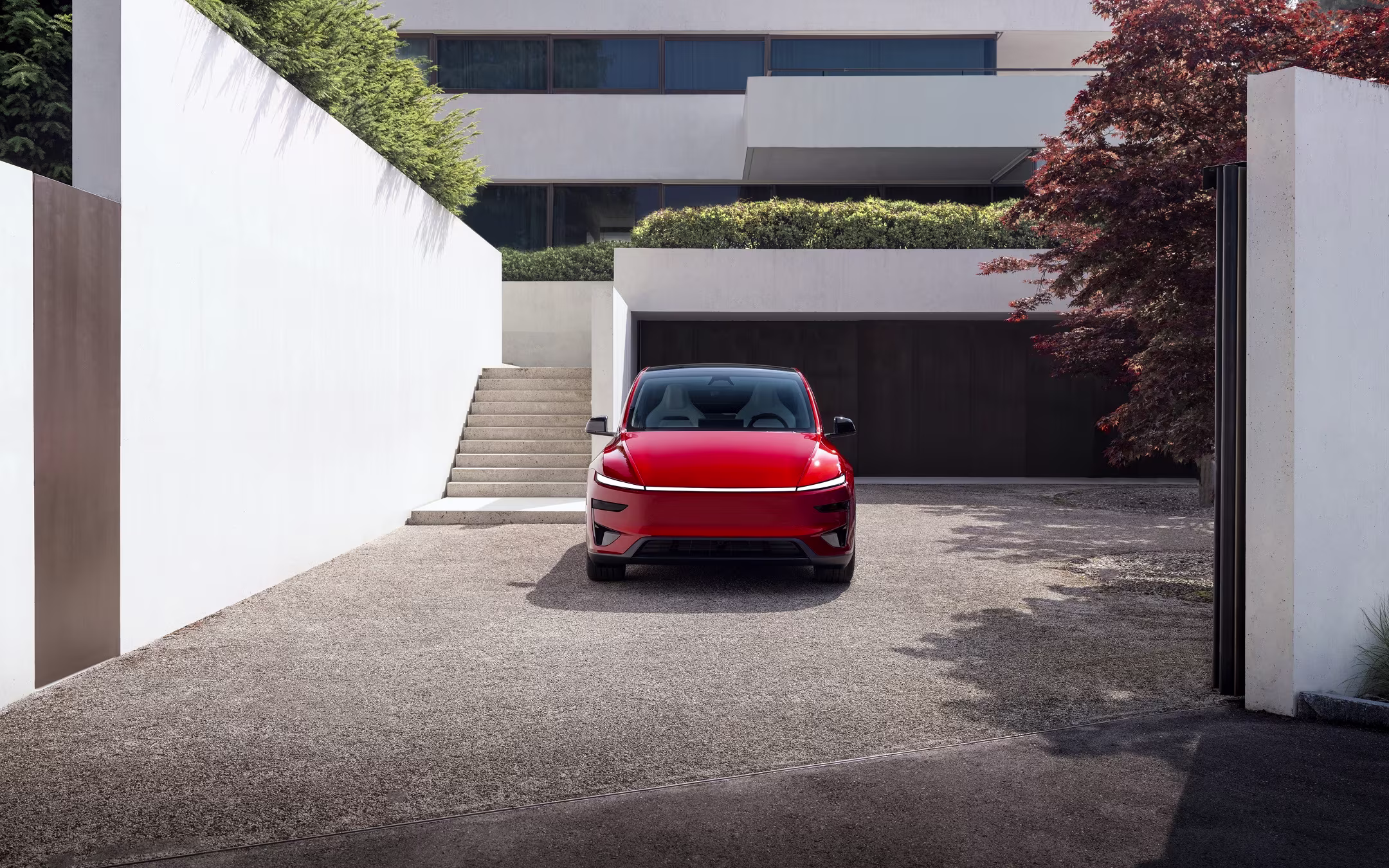 Red Model Y parked in front of a residential garage