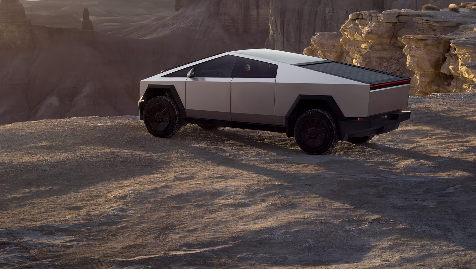 Cybertruck driving off-road in a desert landscape with mountains in the background