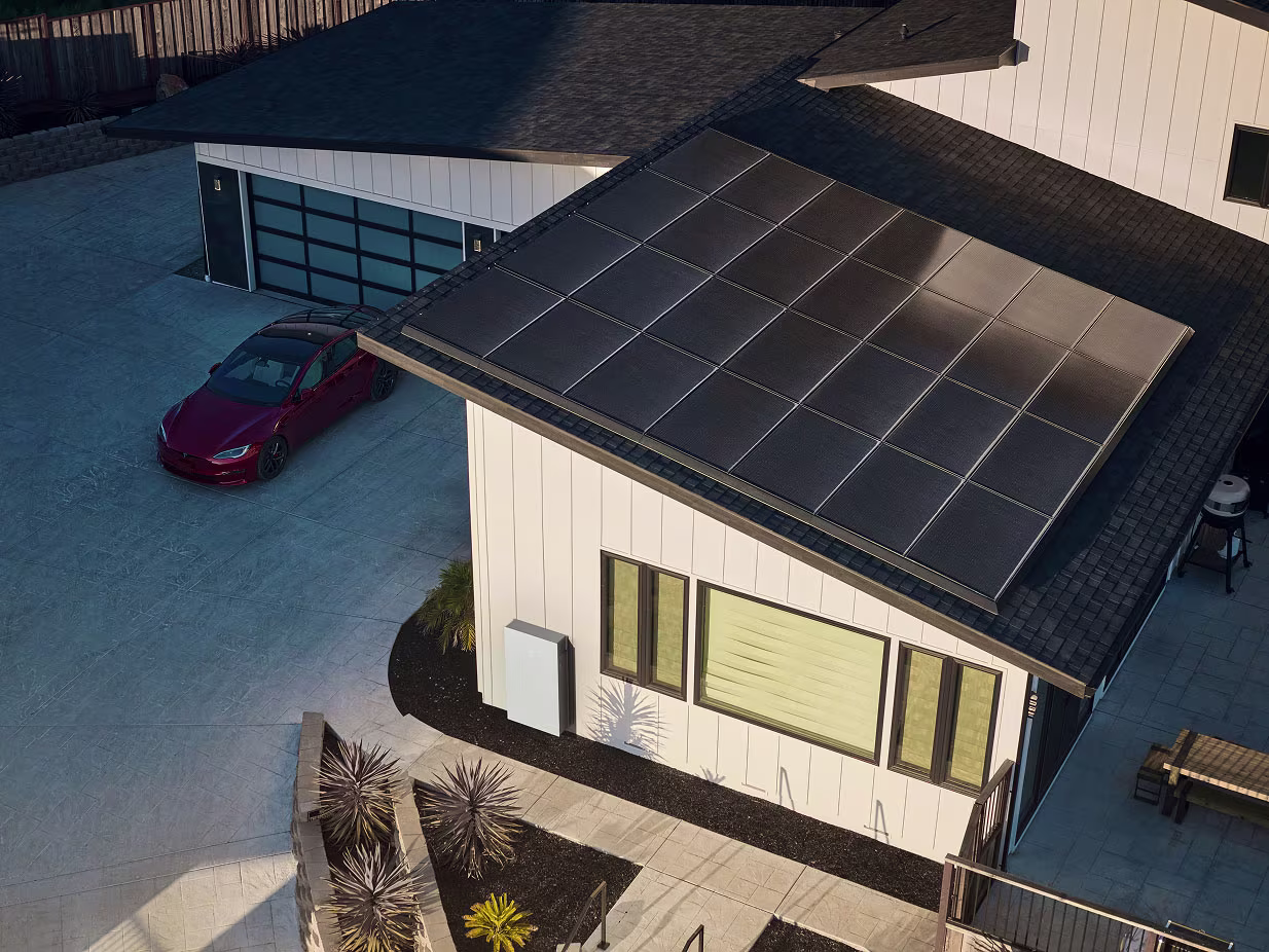 Aerial view of a home with solar panels and red Model S parked outside a home