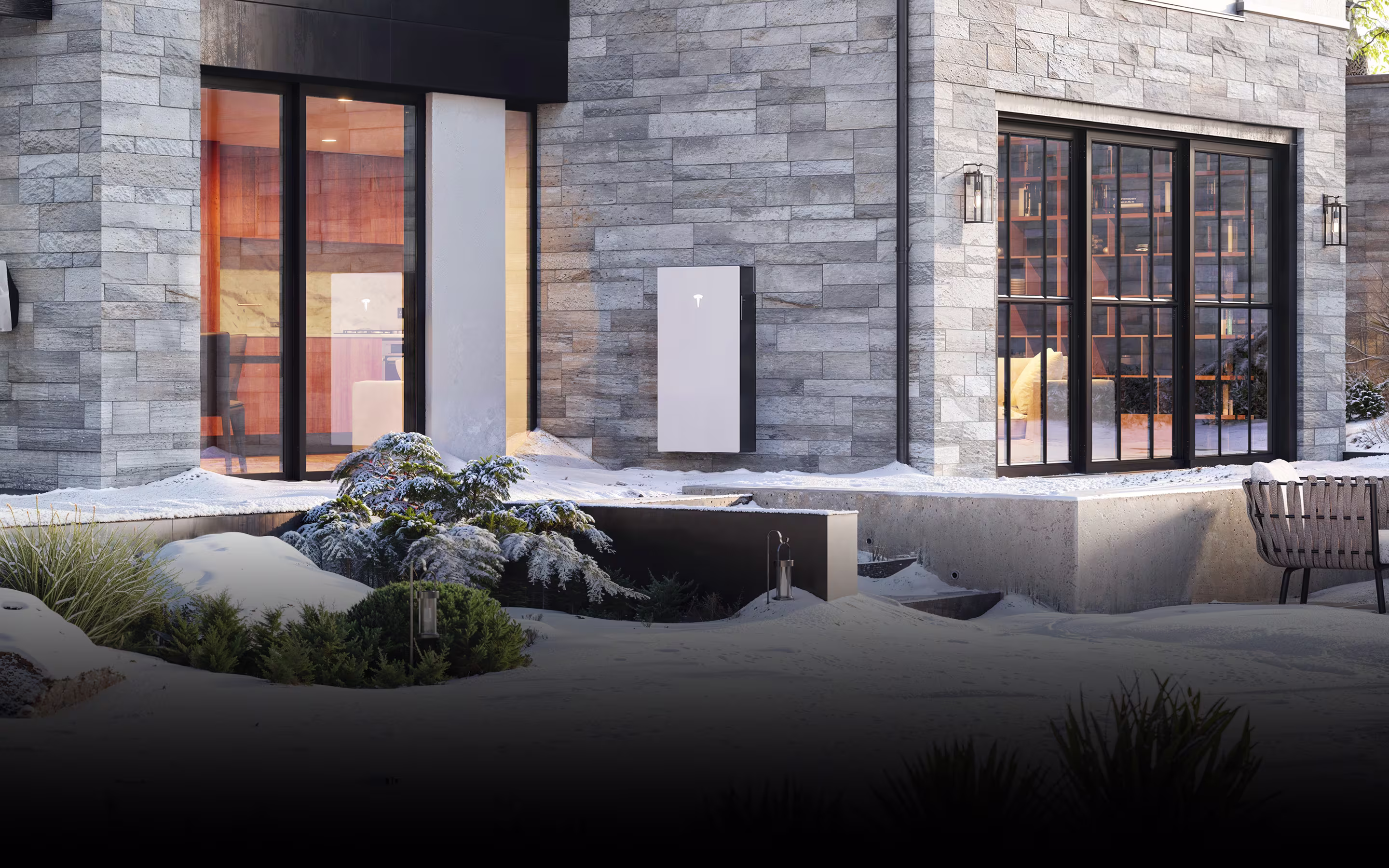 View of a home with snow outside and a Powerwall 3 installed