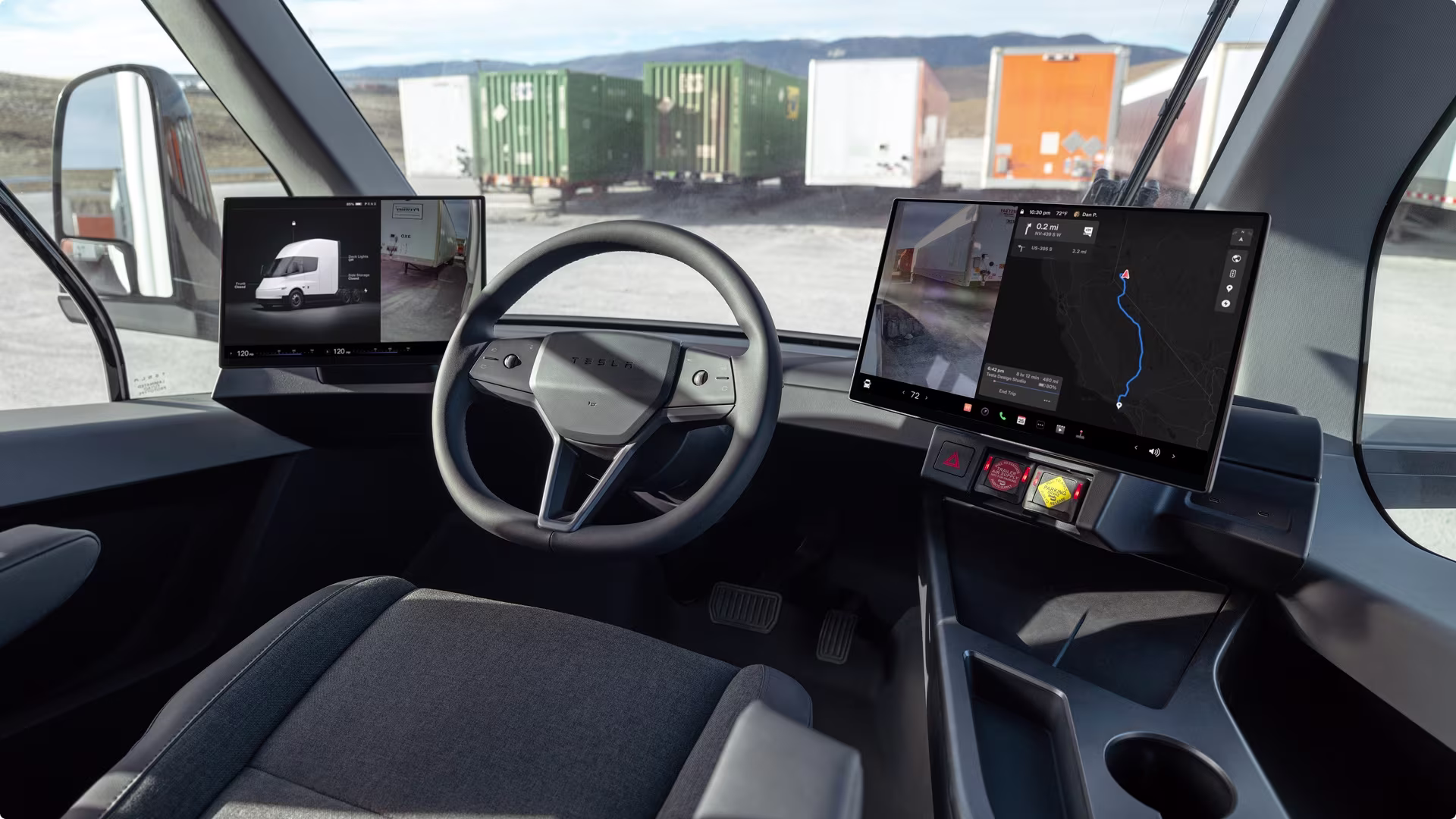 Driver's view of the interior cabin, steering wheel, dual touchscreens and the road ahead. 